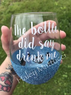 someone holding up a wine glass with the words, the bottle did say drink me