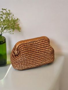 a woven purse next to a green vase