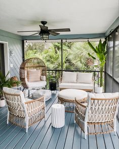 an outdoor living room with wicker furniture and plants on the porch area, overlooking trees