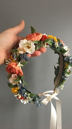 a hand holding a wreath with flowers on it