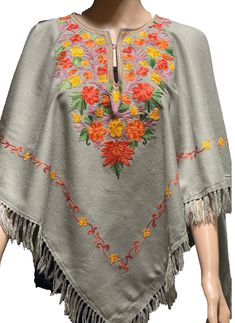 Floral Embroidery  Poncho Crafted from wool blends. Wear it over a shirt, with pants, jeans or leggings.  The exquisite embroidered design is on the front, sides and back.  The Poncho does  not have sleeves or any fittings, the poncho is designed to go over the head and sit around the shoulders free style. the edges have tassel fringes around the entire bottom of the poncho. The neck has an eye and hook, It is also lined with complementing fabric for comfort. The floral multi colored Ari needle embroidery uses  natural plant dye thread.  Color; Ocean blue or stone gray- color can vary due to lighting   Free style Fit Size   42'X42' Shoulder to hem 32' (inch) with Fringe Fabric; Wool Made in a smoke and Pet free home. Made in Kashmir,India Traditional One Size Poncho For Fall, Traditional Shawl Poncho For Fall, Traditional Multicolor Embroidered Shawl For Winter, One Size Embroidered Poncho For Fall, Embroidered Pashmina Shawl For Fall, Traditional Winter Poncho One Size, Embroidered One Size Poncho For Fall, Traditional Shawl For Fall, One Size, Folk Style Poncho For Fall