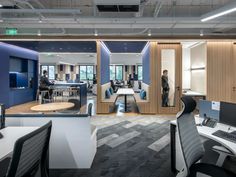 an office filled with desks and chairs next to two men standing in the background