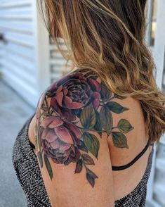 a woman with a flower tattoo on her back shoulder and shoulder is looking down at the ground