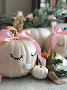 some white pumpkins with pink bows and eyelashes