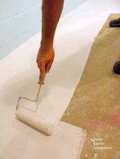 a man is using a paint roller on the floor