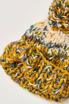 a multicolored knitted beanie sits on a white surface