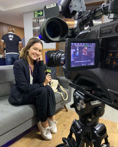 a woman sitting on top of a couch in front of a camera and recording equipment