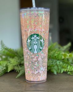 a pink starbucks cup with glitter and a straw