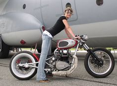 a woman sitting on top of a motorcycle next to an airplane