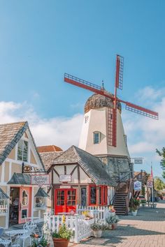 an old windmill sits in the middle of a town with small buildings and tables set up around it