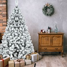 a white christmas tree in front of a fireplace with presents on the floor next to it