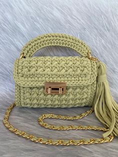 a crocheted purse with a tasselled handle and gold hardware on it