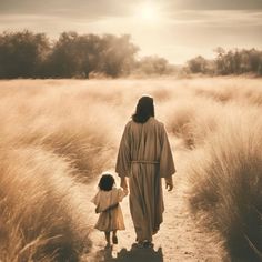 a woman and child walking down a path in the middle of a field with tall grass