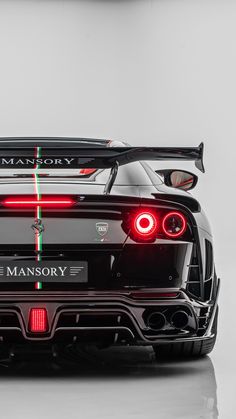 the rear end of a black sports car with red lights on it's taillights