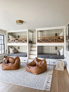 two leather bean bags are on the floor in front of bunk beds and rugs