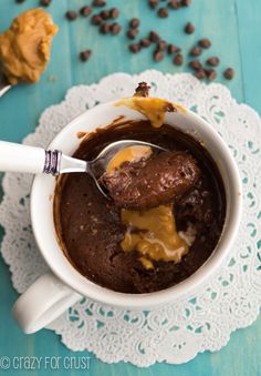 a spoon is in a mug with chocolate pudding and caramel drizzle on it