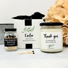 two candles with thank you labels next to a gift box