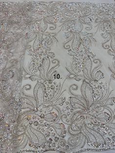 an image of a white fabric with sequins and beads on the bottom half