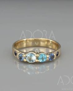 a gold ring with three blue stones on the side and two diamonds in the middle