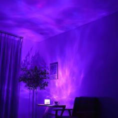 a living room with purple lighting and a black chair in front of a table that has a potted plant on it