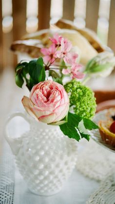 a white vase filled with flowers sitting on top of a table next to other plates