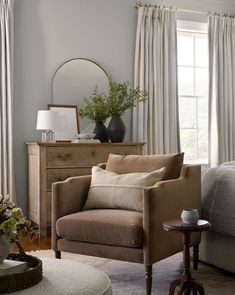 a living room filled with furniture and a mirror on top of a dresser next to a window