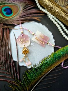 two pink and gold earrings on top of a peacock feather