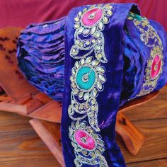 a purple bag with colorful beads and tassels on it sitting on a wooden table