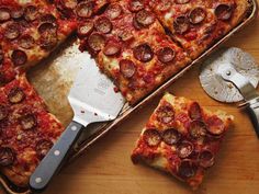 a pizza with pepperoni and cheese cut into slices on a cutting board next to a spatula