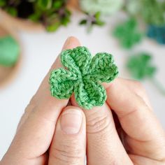 a person holding a green crocheted clover