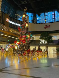 a christmas tree in the middle of a shopping mall with lights and decorations on it