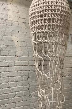 a sculpture made out of white wire on top of a brick wall