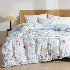 a bed with blue and white flowers on it in a room next to a lamp