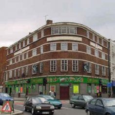 cars are driving down the street in front of a building with green awnings