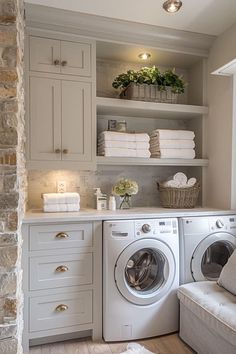 a washer and dryer sitting in a room next to each other with towels on the shelves