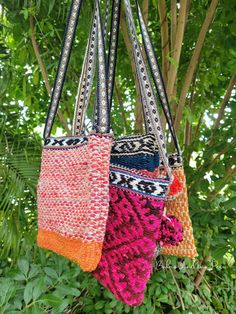 multicolored knitted bags hanging from a tree