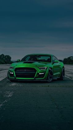 a green sports car parked in a parking lot at night with dark clouds above it