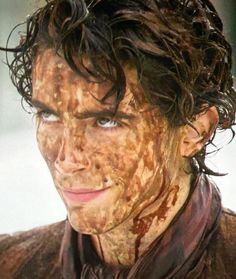 the young man is covered in mud and has his face smeared with brown paint on it