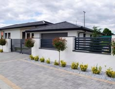 a white house with black shutters on the front and side walls, surrounded by landscaping