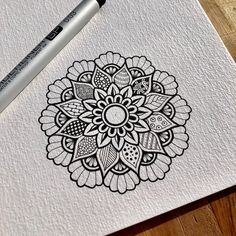 a pen is sitting on top of a piece of paper with an intricate flower design