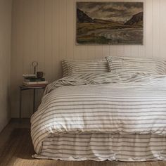 a bed sitting in a bedroom next to a wall with a painting hanging above it