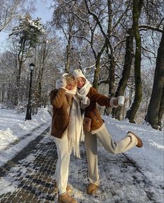 two people standing in the snow with their arms around each other