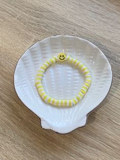 a white plate with a yellow smiley face beaded bracelet on it's side