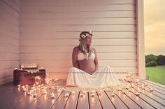 a pregnant woman sitting on a porch with candles in front of her and looking out the window