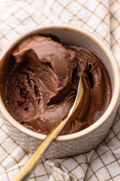 a bowl filled with chocolate ice cream on top of a table next to a spoon