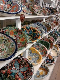 many colorful plates are on shelves in a store