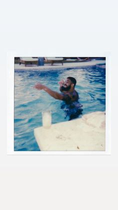 a man is in the water with a frisbee and a drink on his hand