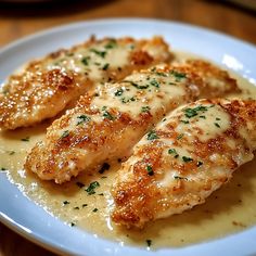 three pieces of chicken covered in gravy on a plate