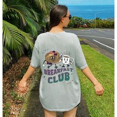 a woman walking down the sidewalk with her back to the camera, wearing a t - shirt that says breakfast club