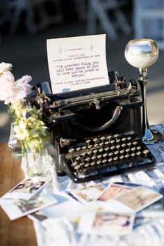 an old fashioned typewriter sitting on top of a table covered in papers and flowers